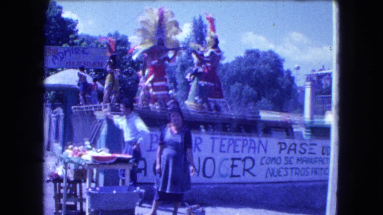 1962 Mexico City home-movie frame showing a parade float with costumed dancers, a Bazar Tepepan Pase banner, vendors, and nearby spectators.