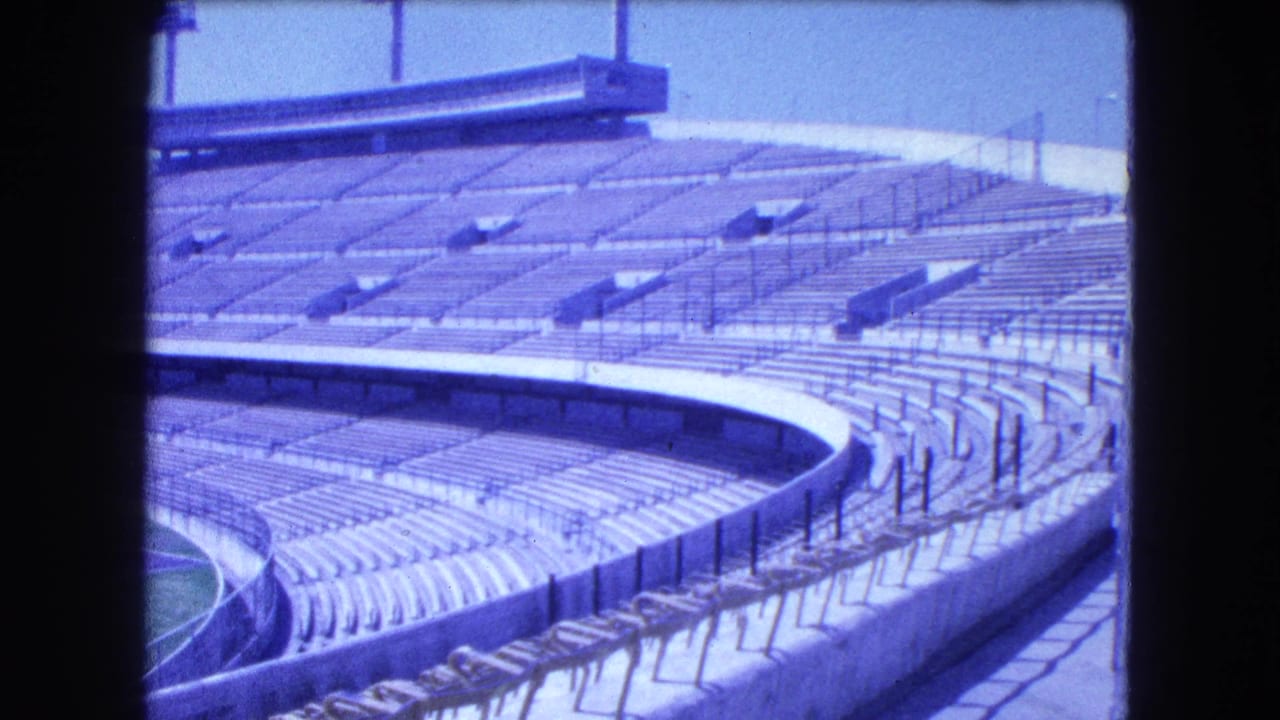 Empty stadium stands with curved lower seating, railings, and upper seating rows.
