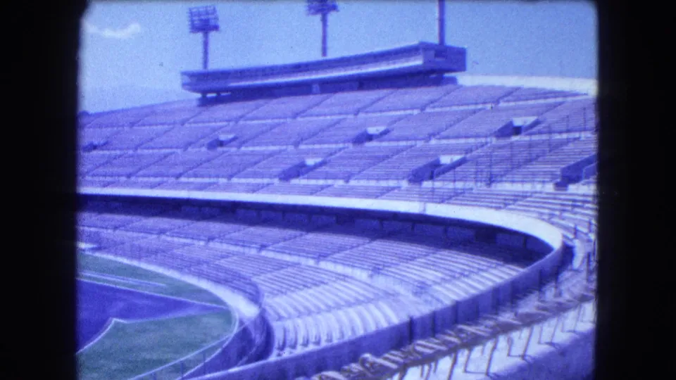1962 Mexico City 8mm view of empty stadium stands, field edge, concrete seating, railings, and a high structure above the rows.