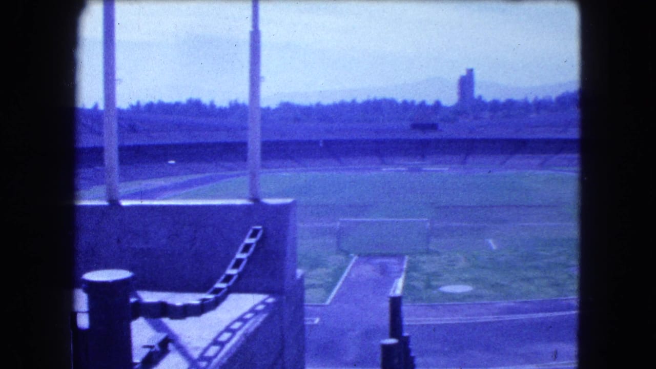 Empty stadium field and running track seen through dark film borders.