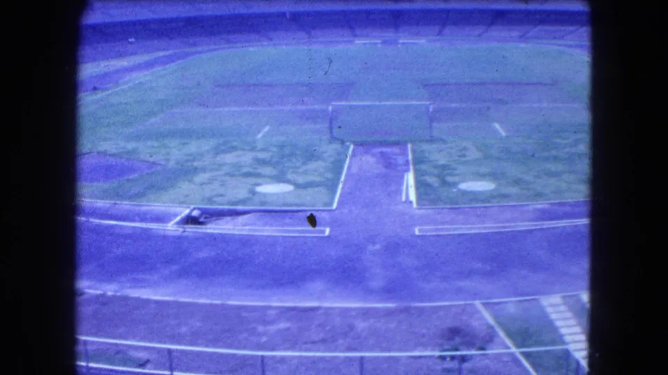 Elevated 1962 Mexico City view of a grassy sports field bordered by a track and empty stadium seating.