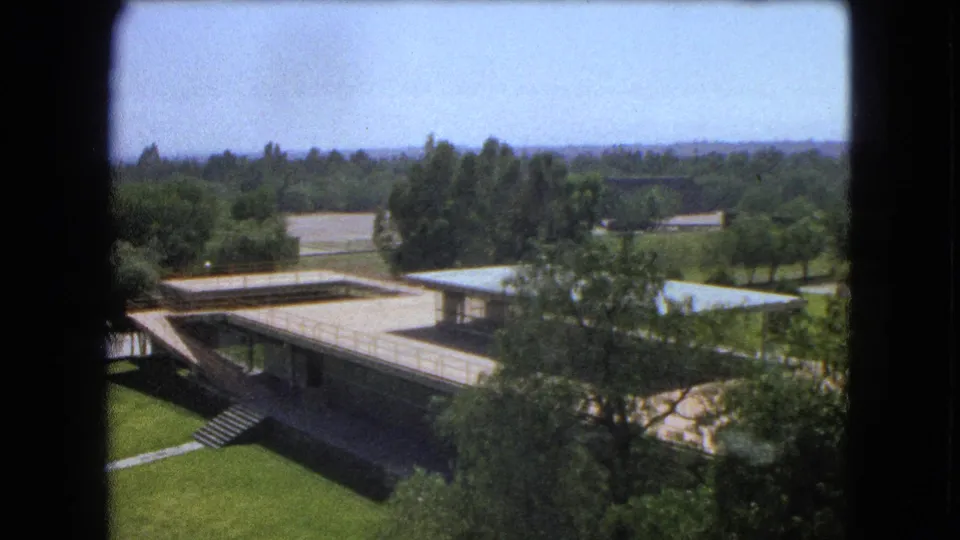 1962 Mexico City campus scene with flat-roofed buildings, exterior stairs, lawns, and trees seen from an elevated viewpoint.
