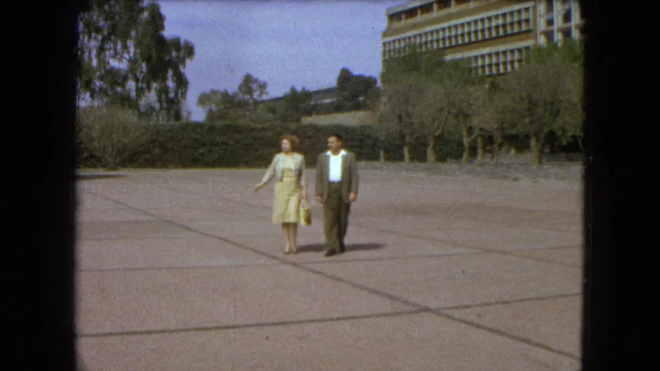 Near the end of the 1962 Mexico City clip, the couple approaches the camera across the sunlit paved esplanade.