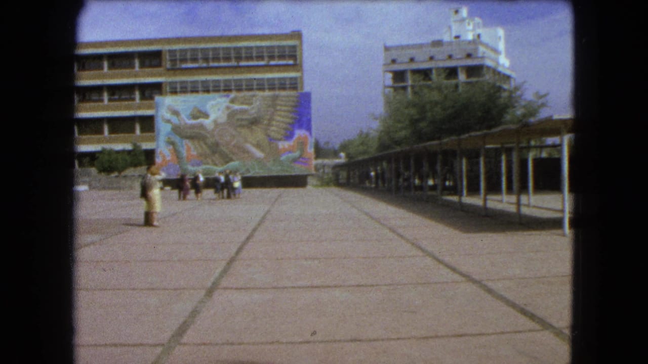 Mexico City plaza in 1962 with a large colorful mural, modern building facade, breezeway, and several people in the open space.