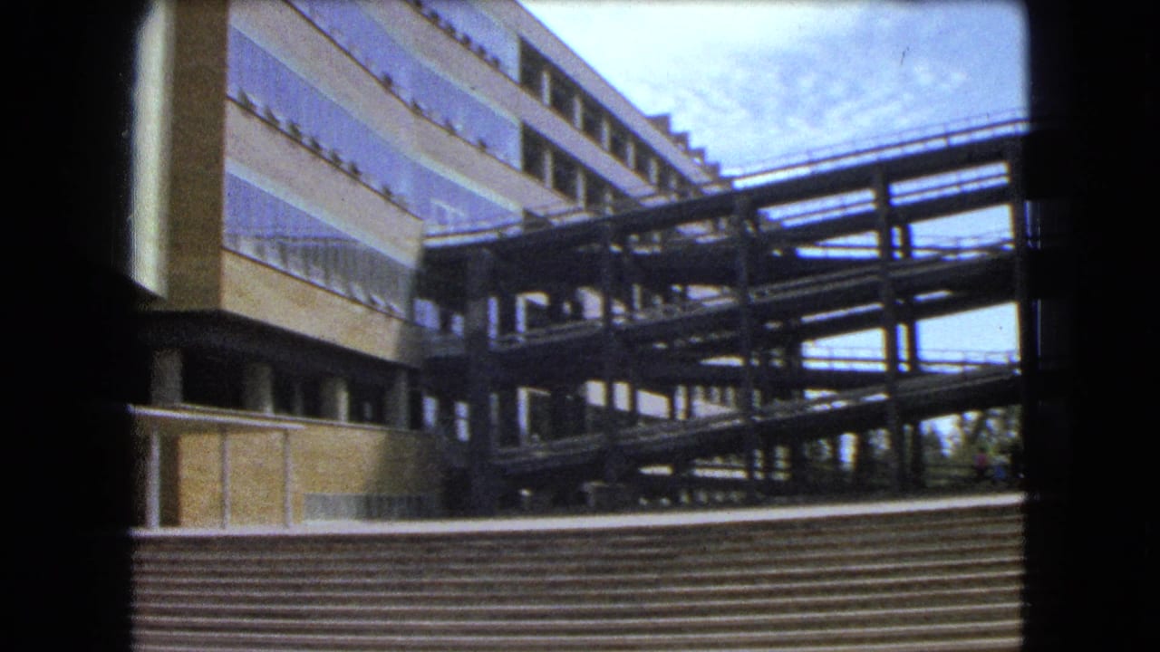 Modernist building exterior with broad steps, window bands, and an elevated walkway.