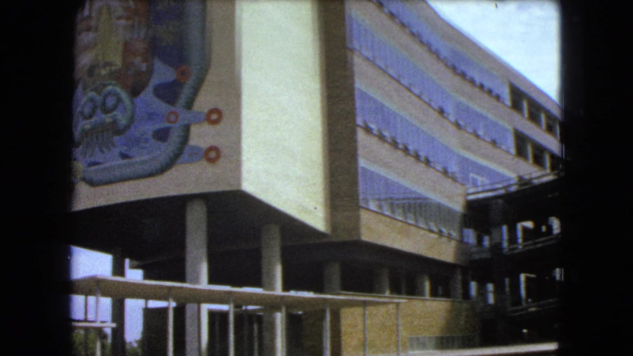 Building corner with columns, windows, railings, and a colorful abstract mural.