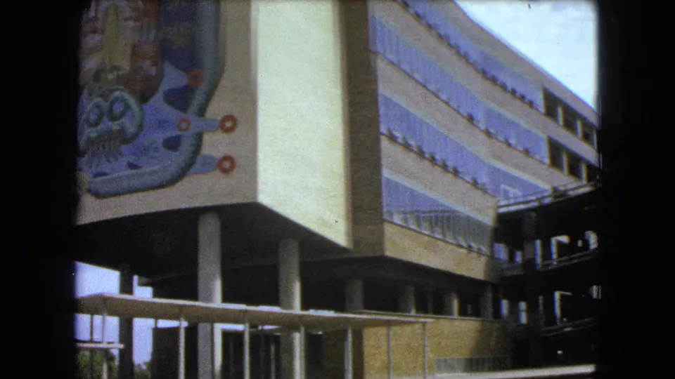 1962 Mexico City view of a modernist building corner with columns and a large abstract mural on the facade.