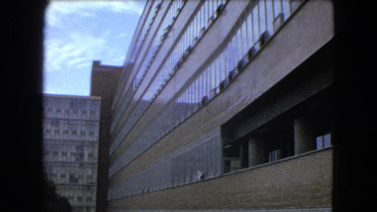 High-rise facade runs diagonally beside a taller background building under a blue sky.