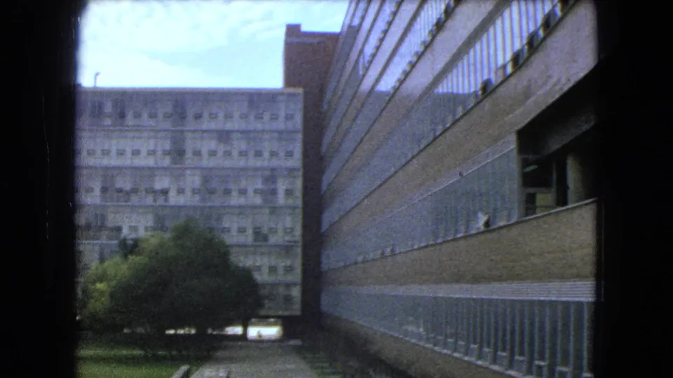 1962 Mexico City 8mm frame showing trees, lawn, walkway, and high-rise buildings in a modern urban setting.