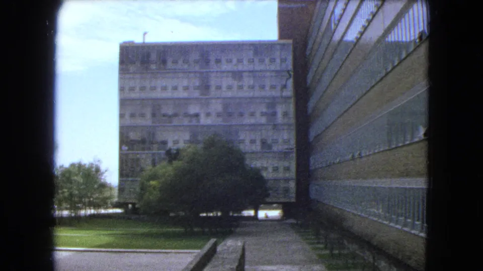 1962 Mexico City frame showing a landscaped space between modern high-rise structures with concrete and glass facade details.