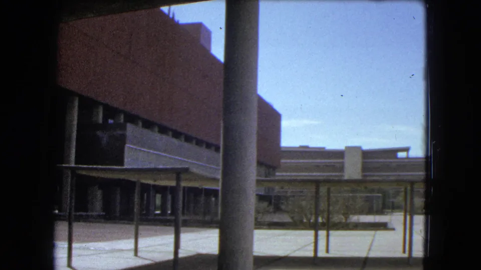 Mexico City school exterior with columns and a paved courtyard, captured on faded 8mm color film.