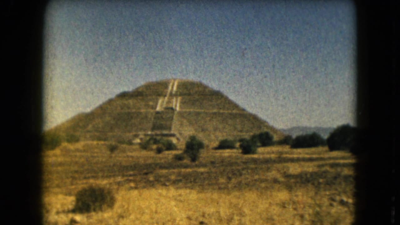 Vintage 8mm frame of the Pyramid of the Sun area near Mexico City, with the structure centered beyond dry open ground.