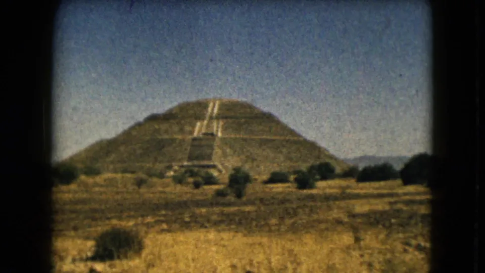1962 home-movie frame showing the Teotihuacan pyramid landscape from a visitor’s distant ground-level perspective.