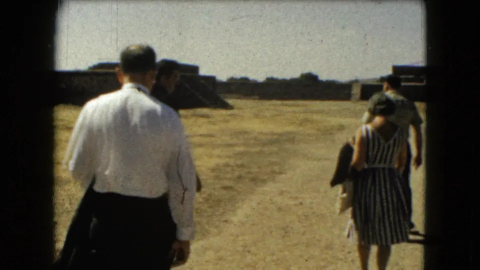 A man and woman walk away from the camera across the dry grounds of a Mexico City archaeological site in 1962.