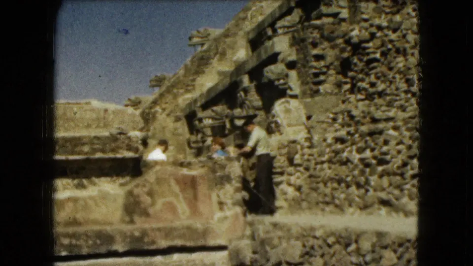 The couple remains near a low wall within the ruins, with carved stone details and textured masonry visible behind them.