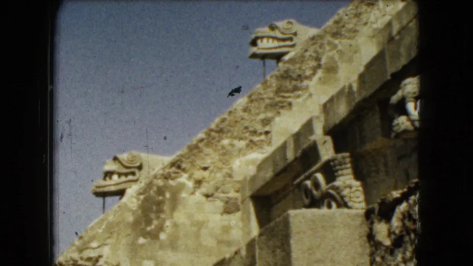 A closer 8mm view shows stepped stone architecture and serpent-like carved forms at a Mexico City ruin site.