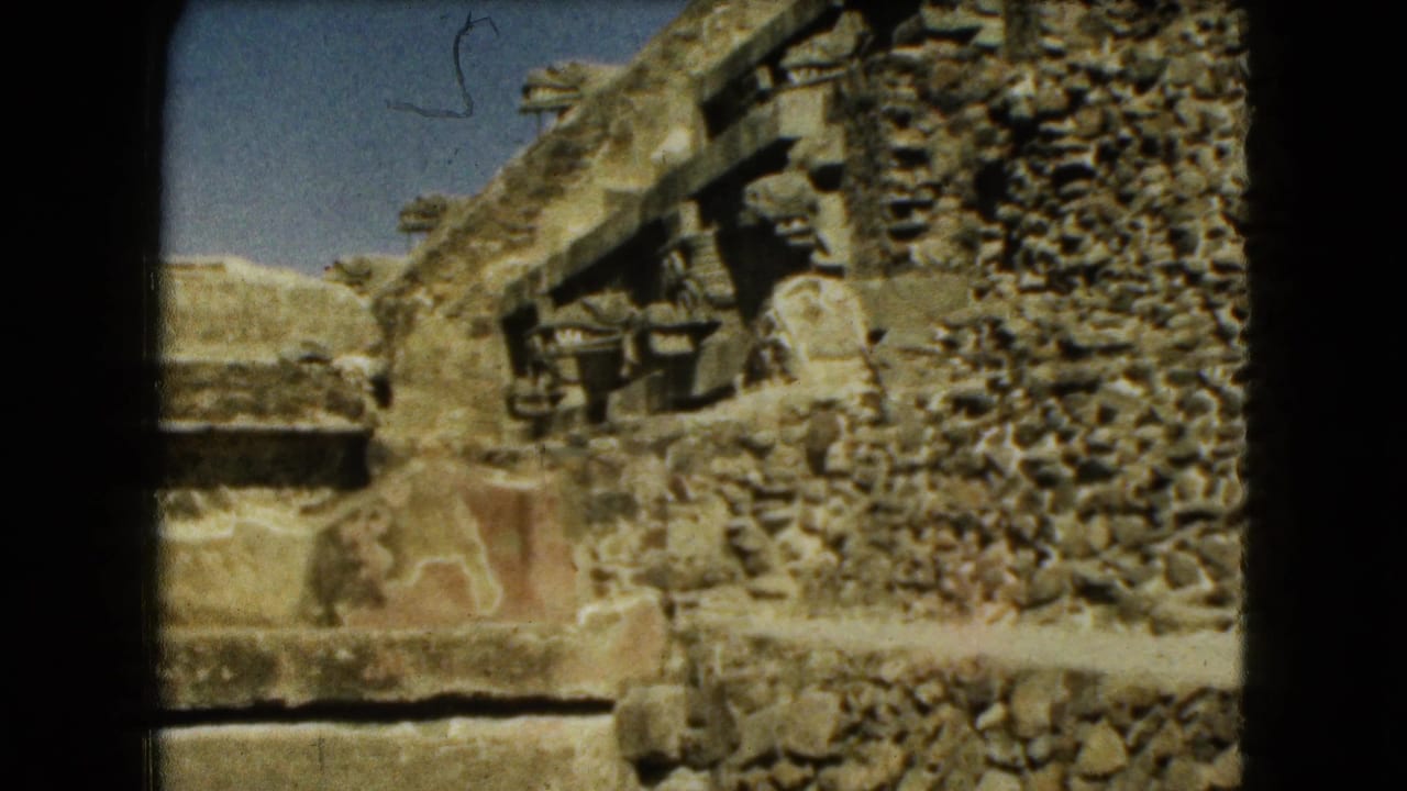 Sunlit stone ruins with carved details and rough masonry under a blue sky.