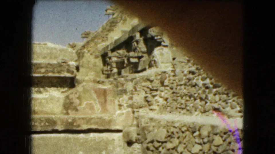 1962 Mexico City home-movie frame of stone ruins, partly covered by a finger or obstruction crossing the lens.