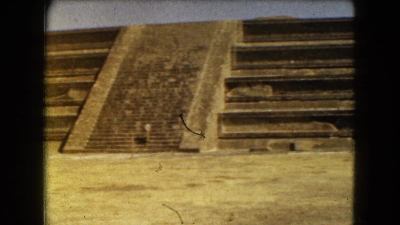 Steep central pyramid steps with adjacent stone terraces under bright sun.