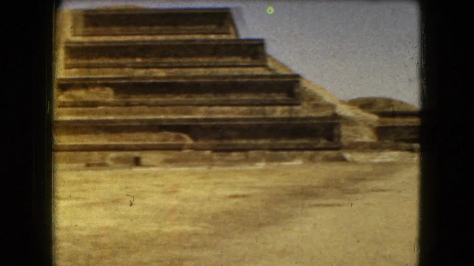 1962 home-movie view of lower stone terraces at Teotihuacan, with open plaza ground in front.