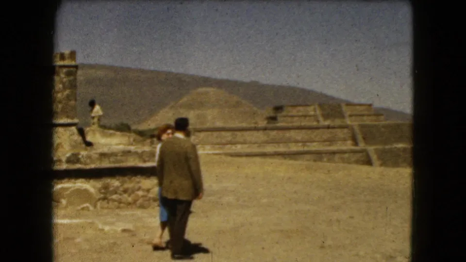 A couple at a Mexico City pyramid complex in 1962, with the woman partly visible beside the man near stone ruins.