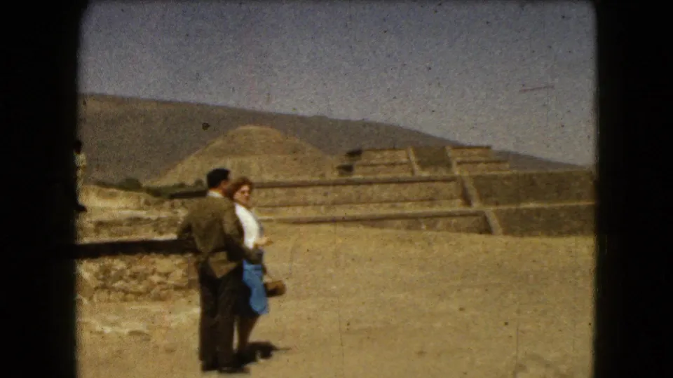 The couple pauses at the ancient ruins near Mexico City, framed by stepped structures and an earthen mound.