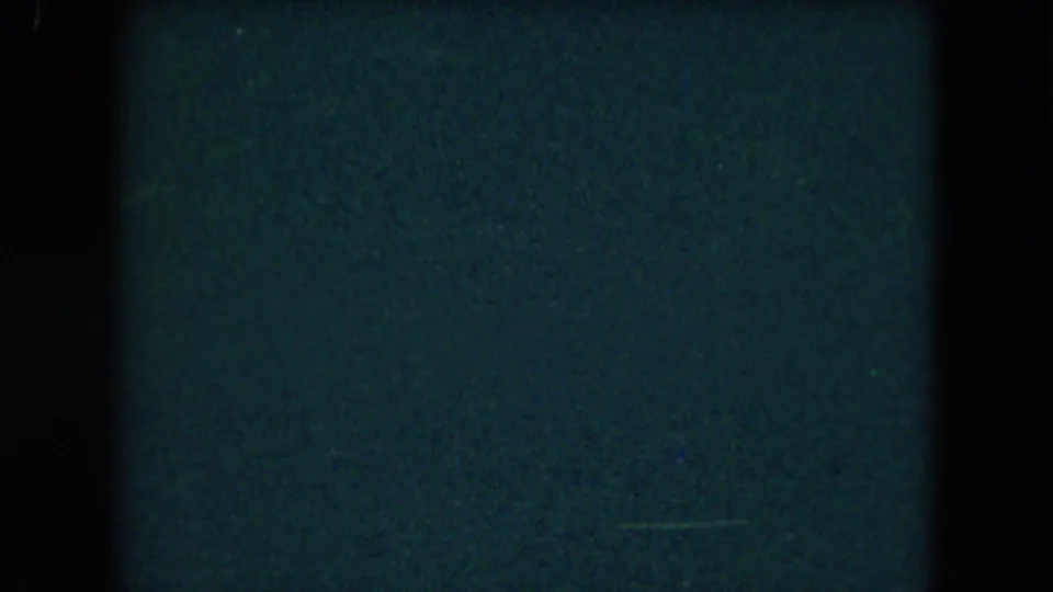 A mostly blank 8mm frame with blue-green exposure, heavy dark borders, and no identifiable people or location details.