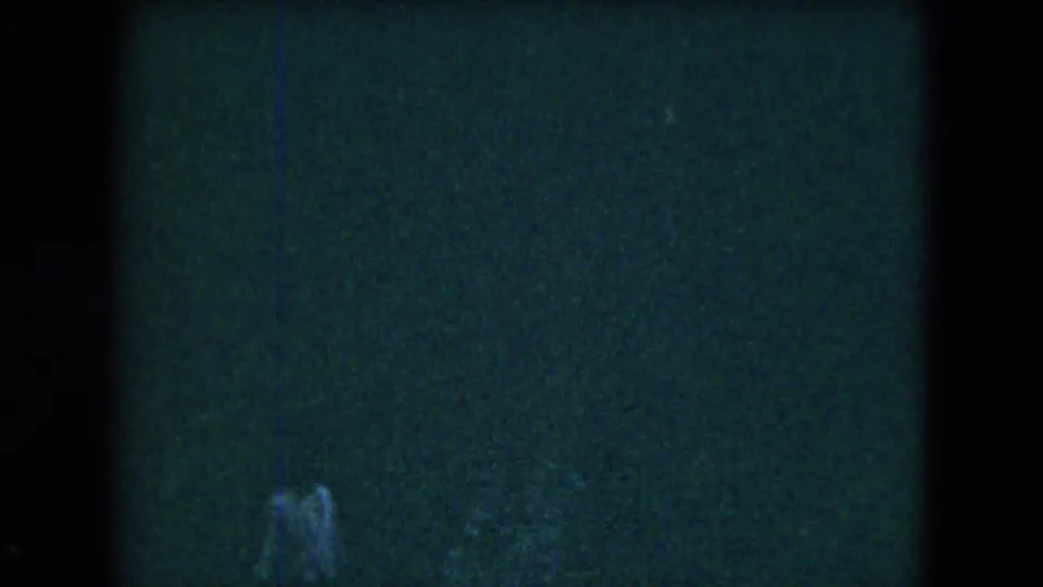 A faint person is visible near the lower edge of a dark, underexposed 8mm frame from Mexico City in 1962.