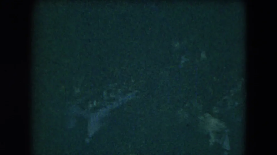 1962 Mexico City 8mm frame with faint silhouetted figures in a dark party hall, softened by grain and low light.