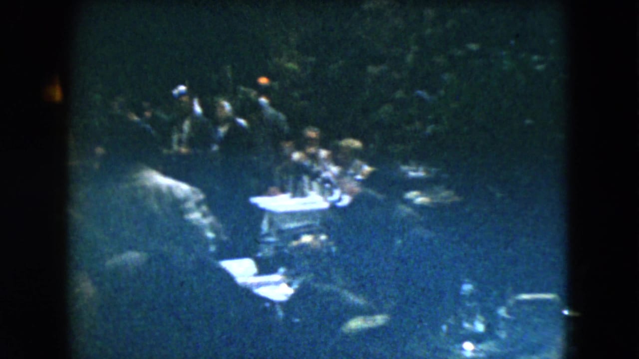 Dim restaurant interior with seated patrons at small tables in low light.