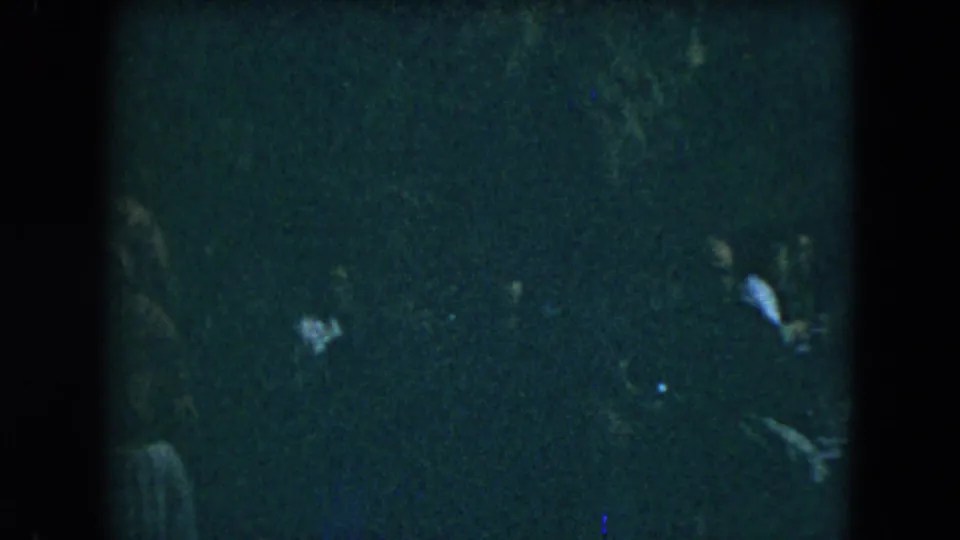 Low-exposure 1962 Mexico City frame with a person partly visible near the right edge of a dark indoor scene.
