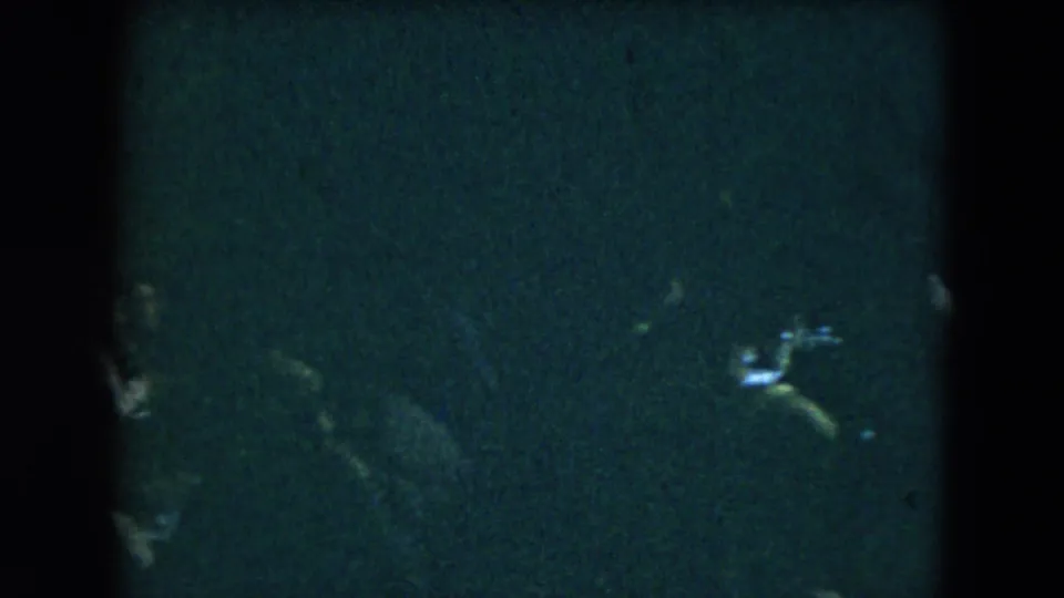 Dim 1962 Mexico City home-movie frame with a partially obscured person or object near the lower right in heavy grain.