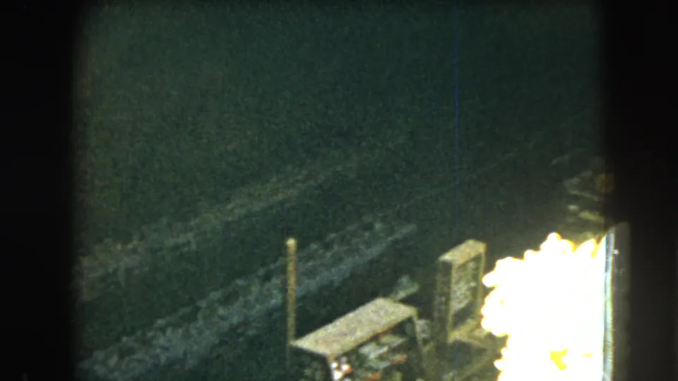 1962 Mexico City home-movie frame with rough stonework, a vertical post, and bright overexposed sunlight at the edge.