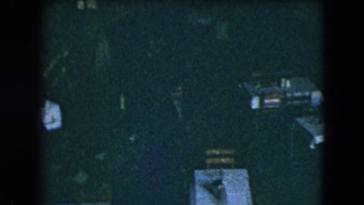 Dim overhead view of white-clothed tables and chairs in a dark restaurant room.