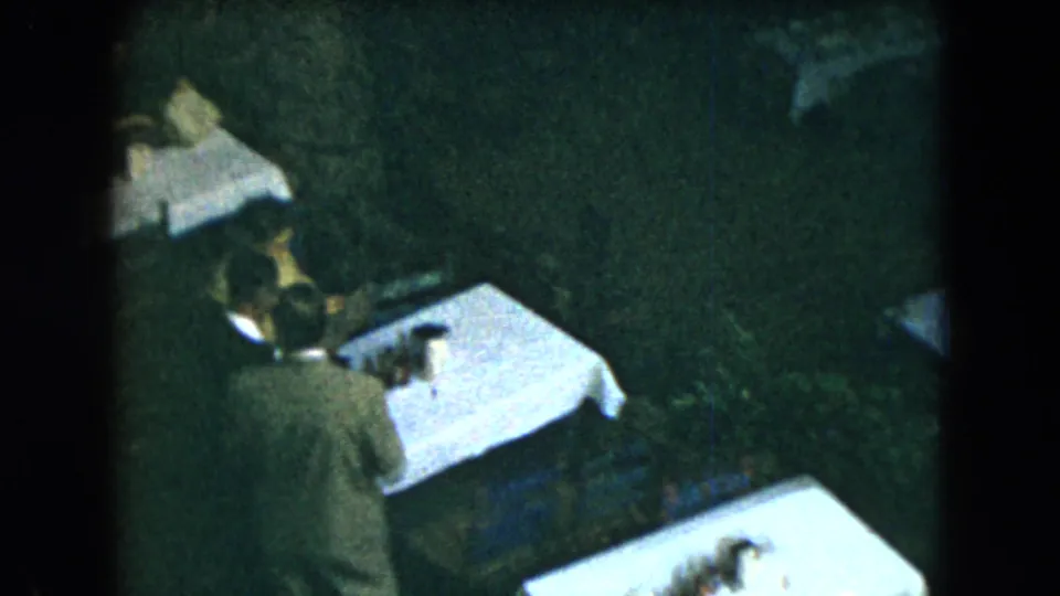 A worker seen from behind stands beside a white-covered table in the 1962 Mexico City restaurant footage.