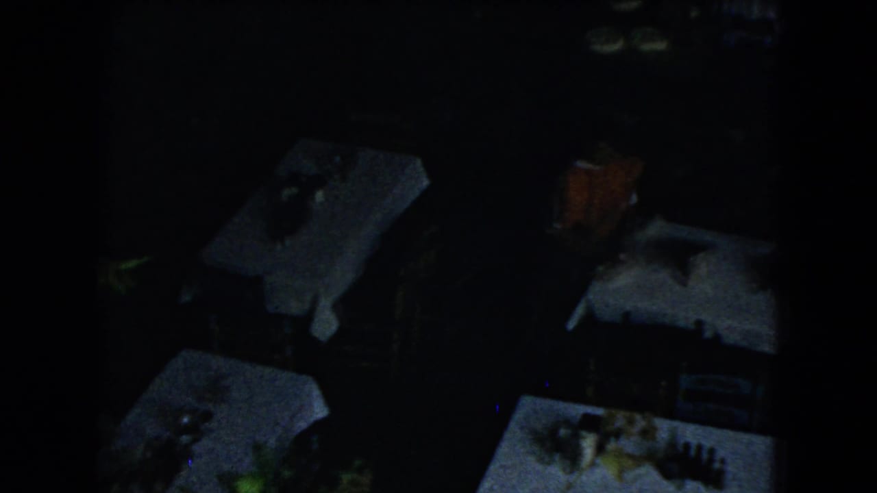 Dark restaurant interior or shaded dining area with white tablecloths and place settings.