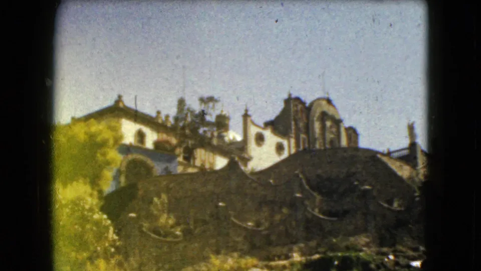 Supplied 1962 Mexico City frame showing church-like architecture, curved masonry, foliage, and a soft handheld 8mm look.