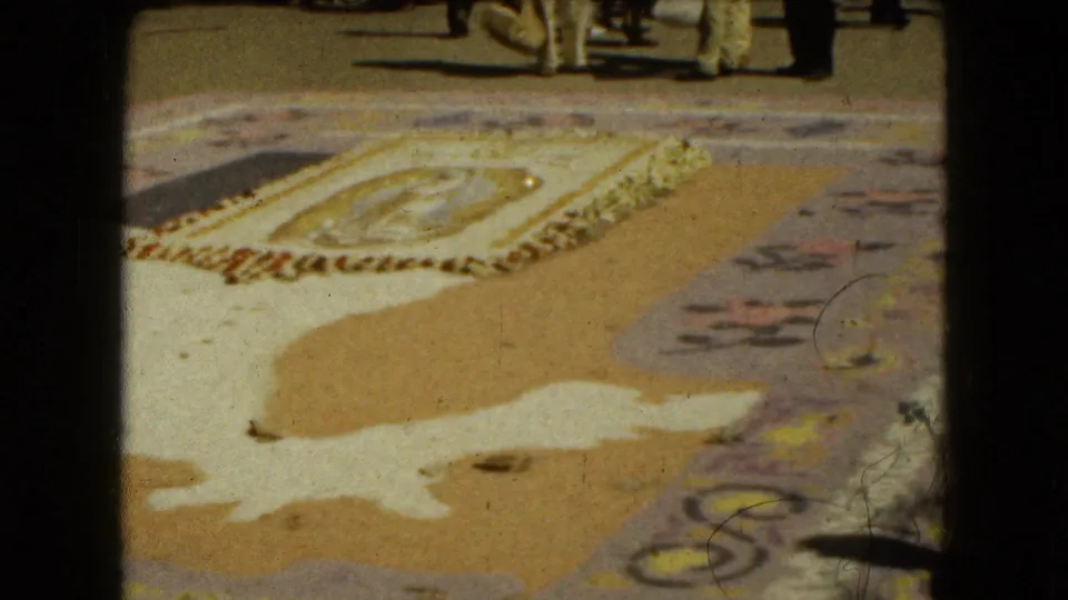 1962 Mexico City frame showing an ornate pavement display with people partly visible at the top edge, likely watching or standing nearby.