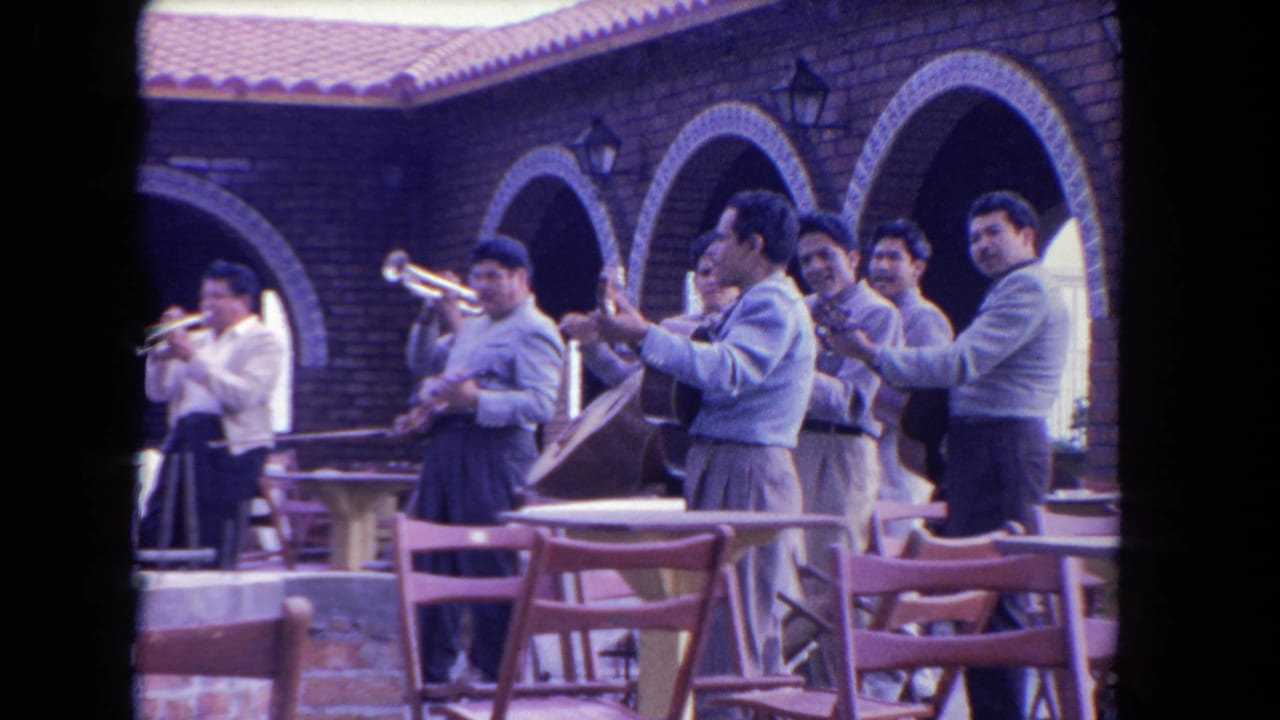 A mariachi group performs in an outdoor Los Angeles courtyard, with brick arches and patio chairs visible around them.