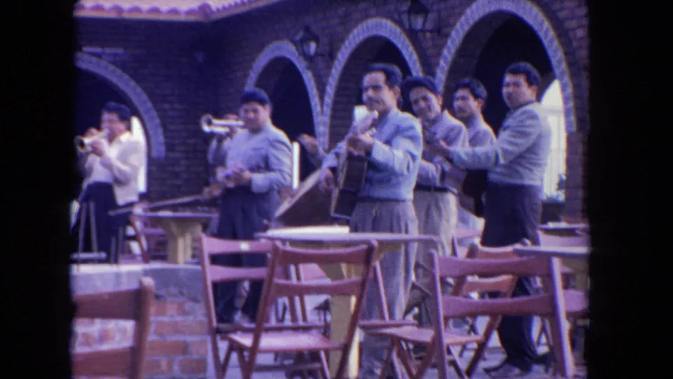 The band remains framed by brick arches and terrace seating, with several adult musicians facing the camera.