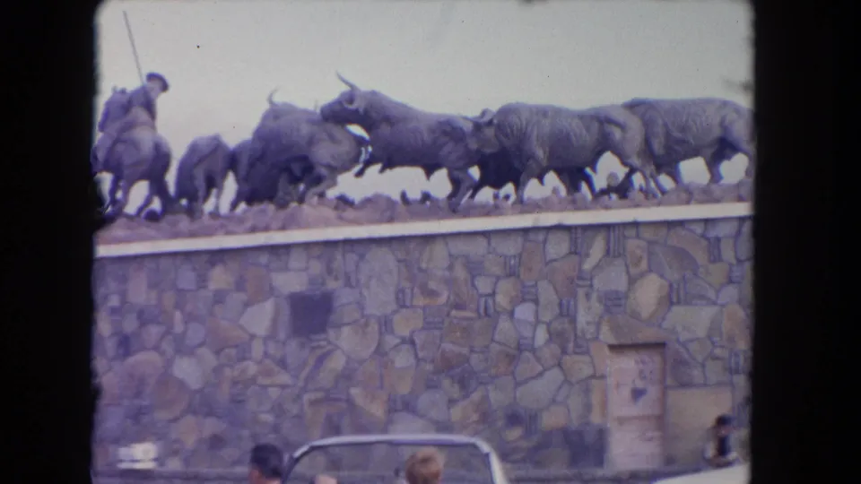 A stone wall displays a dramatic bull-and-matador sculpture, likely part of the same Los Angeles cultural setting shown in the clip.