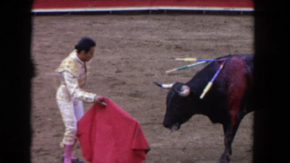 1962 Los Angeles frame showing the matador facing the bull at close range, with colorful banderillas visible on the animal's back.
