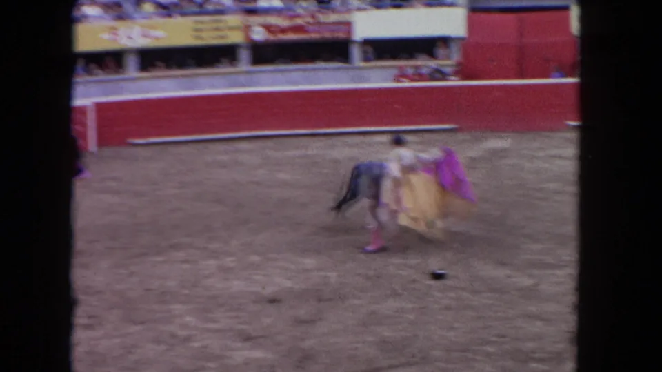 1962 Los Angeles frame showing a matador in a gold-toned costume using a cape near a bull inside the red-walled arena.