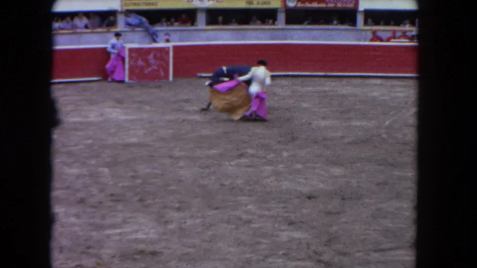 1962 Los Angeles 8mm frame with a matador close to the black bull, a pink cape, and a second performer near the wall.