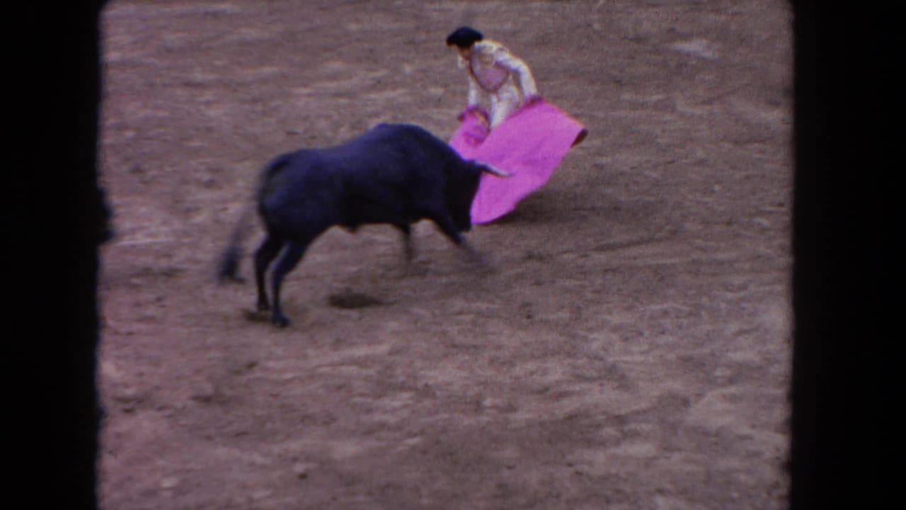 1962 Los Angeles bullfight frame with a matador in white guiding a bright pink cape as a black bull approaches on the dirt ring.