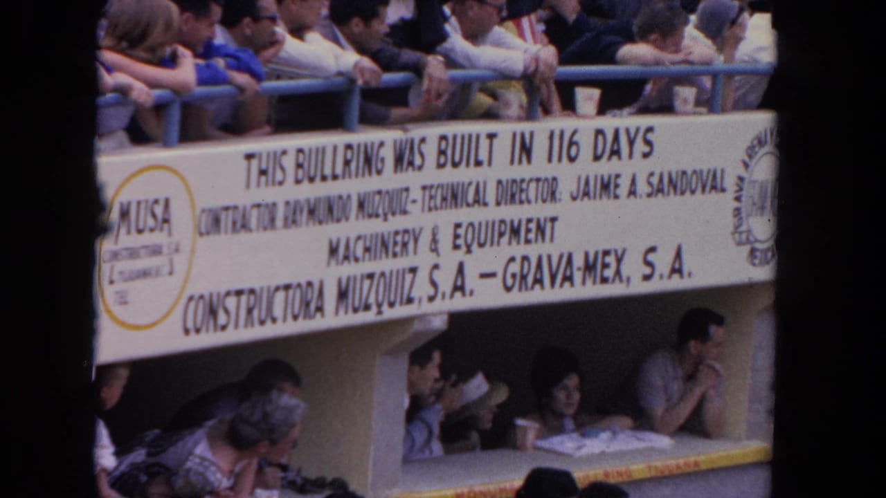 Bullring construction sign above seated spectators in an arena stand.
