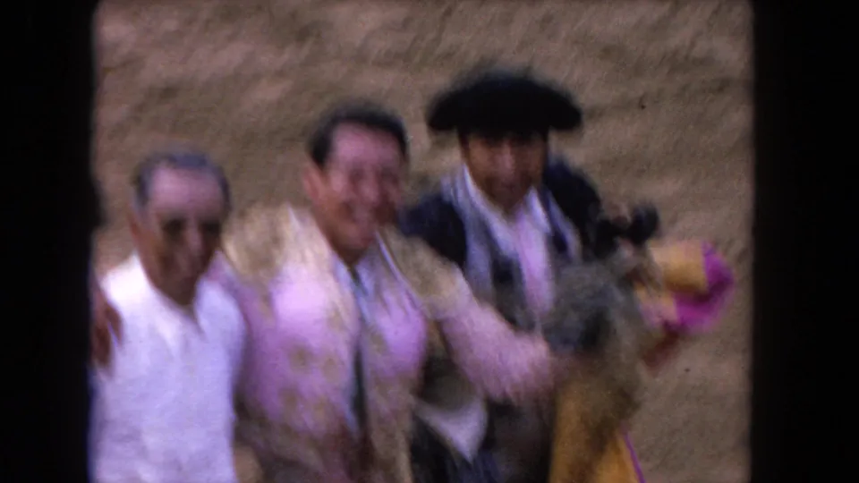 1962 Los Angeles 8mm frame showing men close to the camera, with a bullfighter in pink and white between companions.