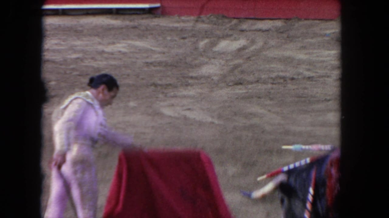 1962 Los Angeles 8mm frame with a matador bending over a red cape while the bull appears at the right side of the ring.