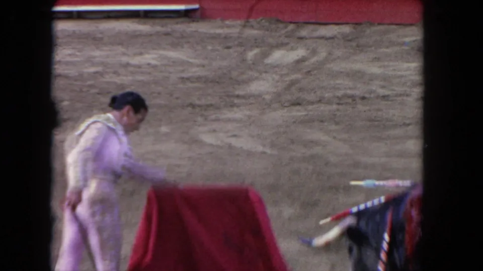 1962 Los Angeles 8mm frame with a matador bending over a red cape while the bull appears at the right side of the ring.