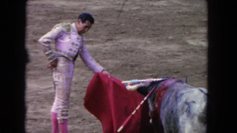 1962 Los Angeles 8mm frame showing the matador lowering a red cloth while the decorated bull approaches.